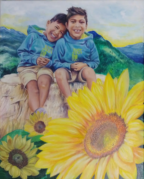 Two children in blue hoodies sitting on a rock with sunflowers and mountains in the background.